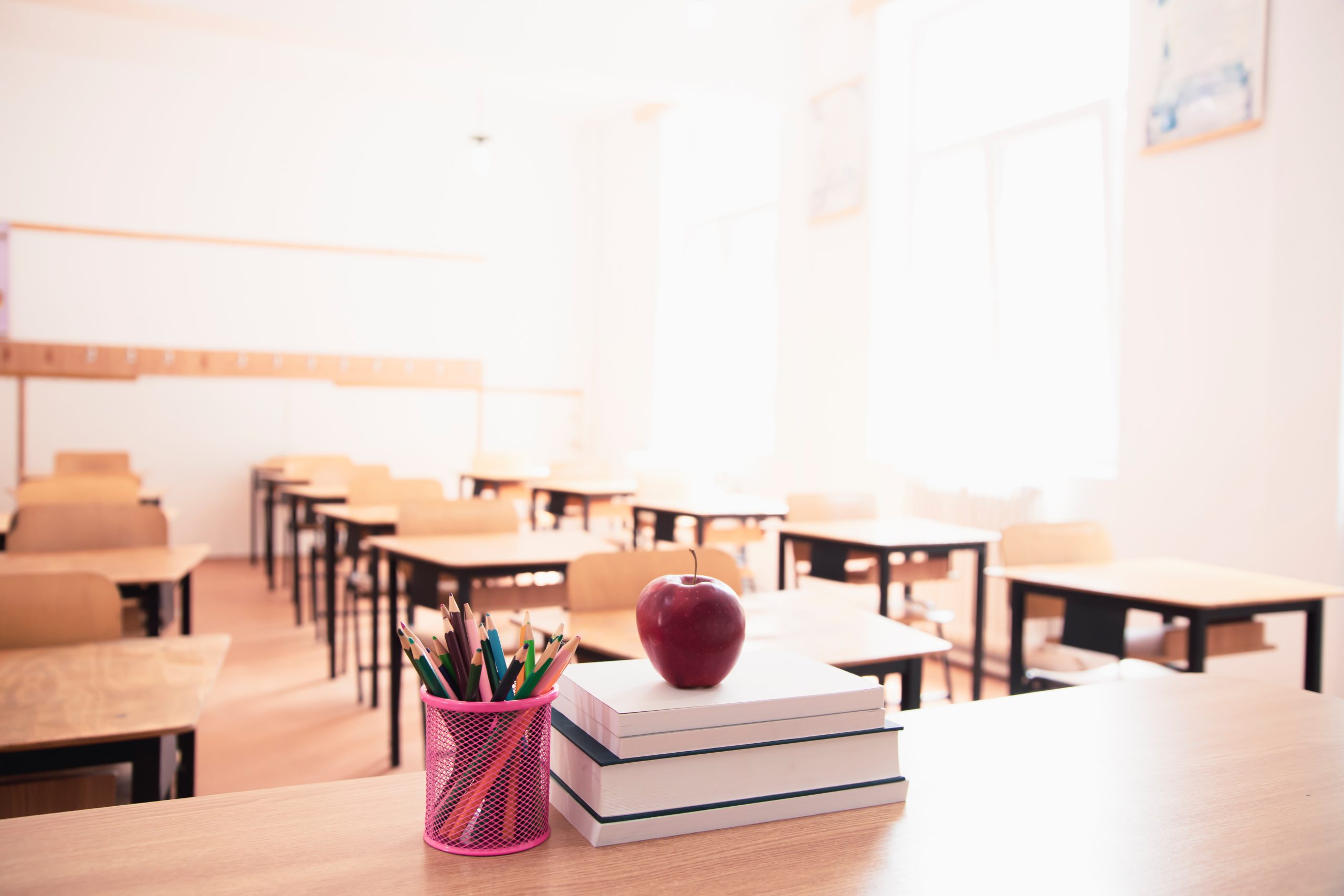 school room with tables and teachers table with apple on it